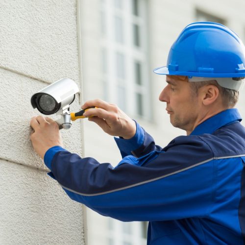 Mature,Male,Technician,Installing,Camera,On,Wall,With,Screwdriver